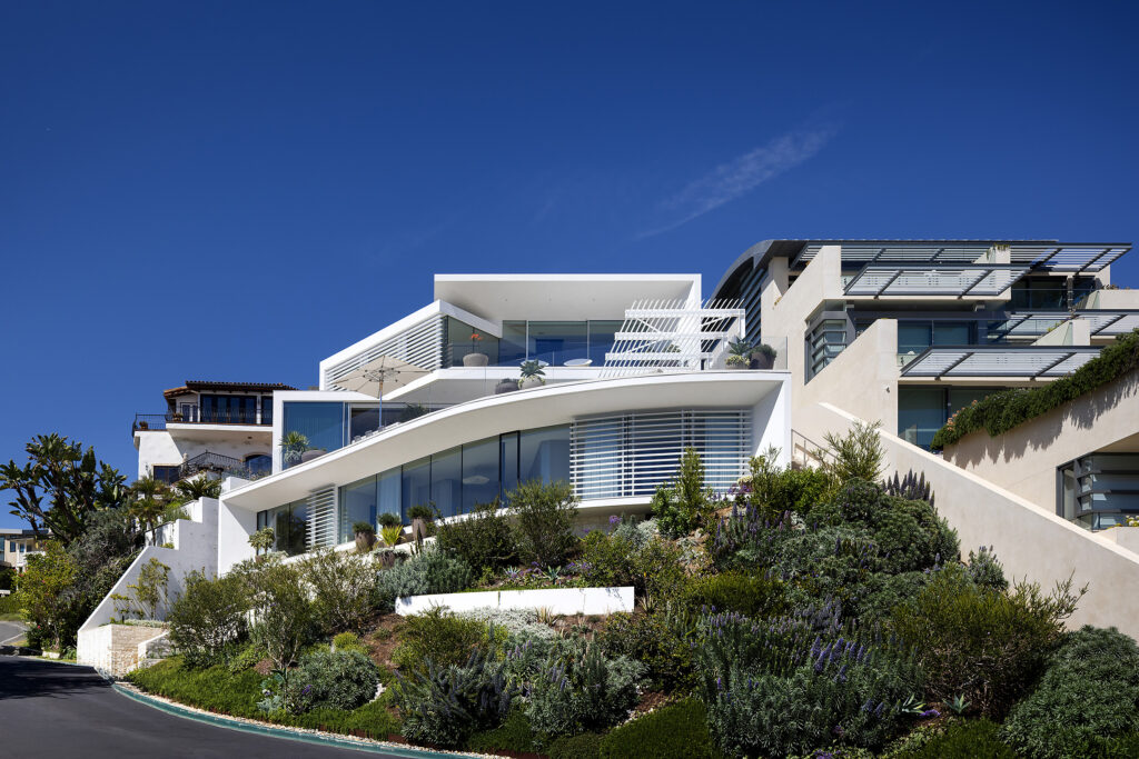 Emerald Bay 1 hillside home with stepped white terraces and glass walls.